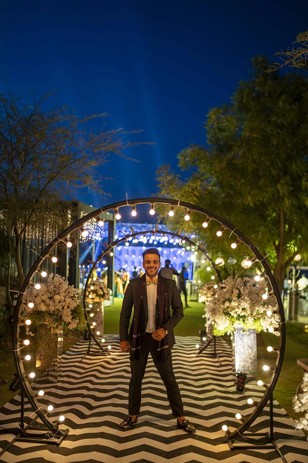 Chirag Vithalani inside a lit floral arch at a night wedding
