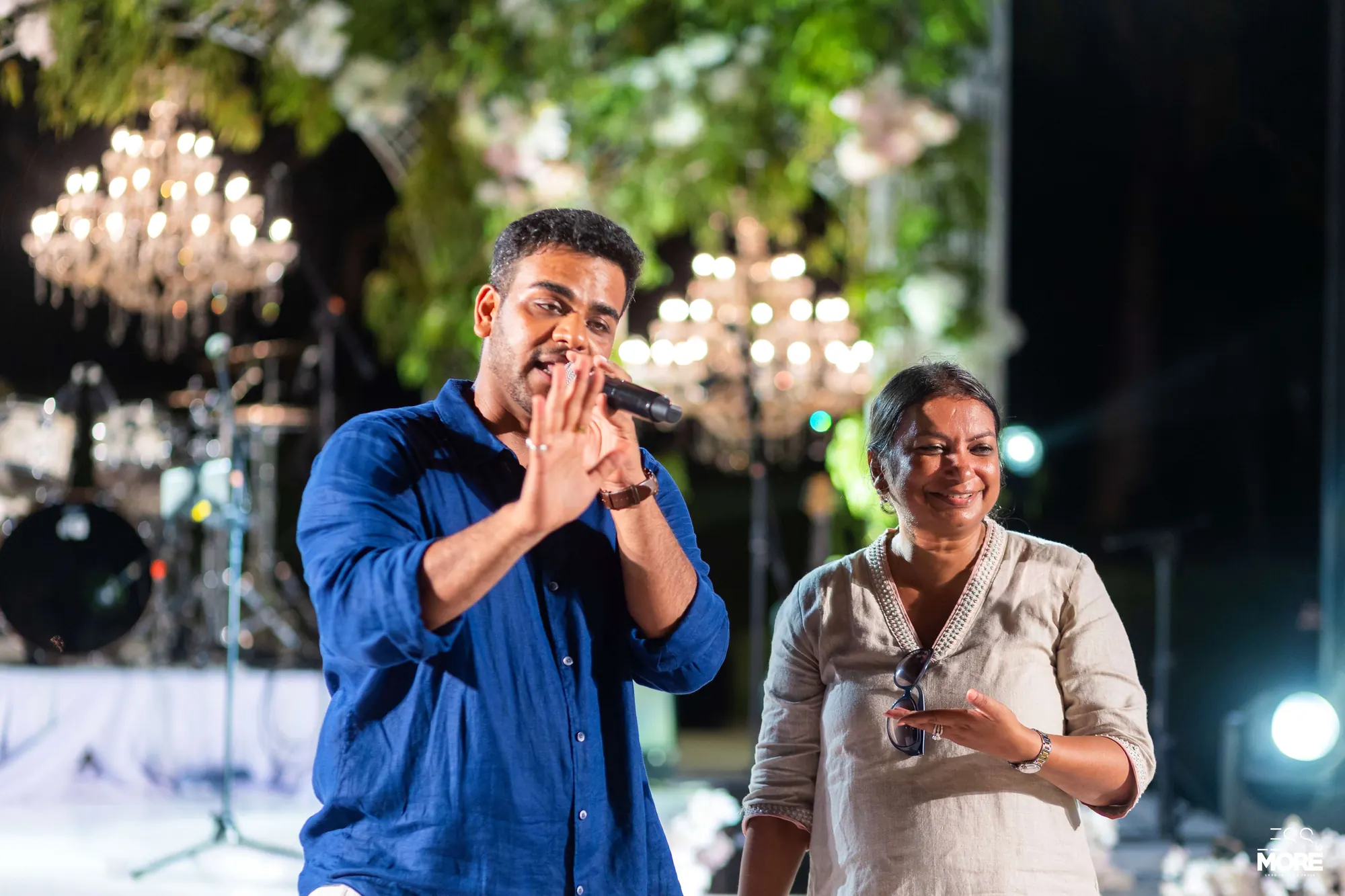 Chirag Vithalani singing with a guest under chandeliers at Aayush and Shama's wedding, Bali