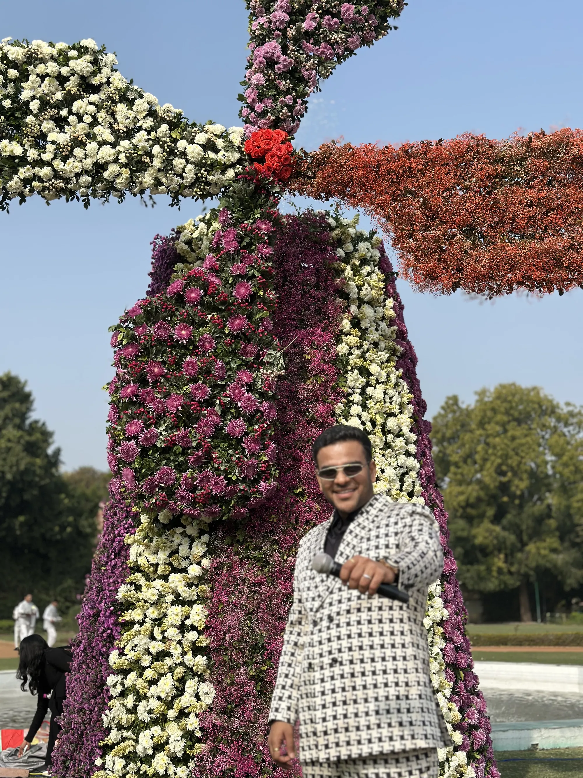 Chirag Vithalani in a houndstooth suit by a floral windmill installation