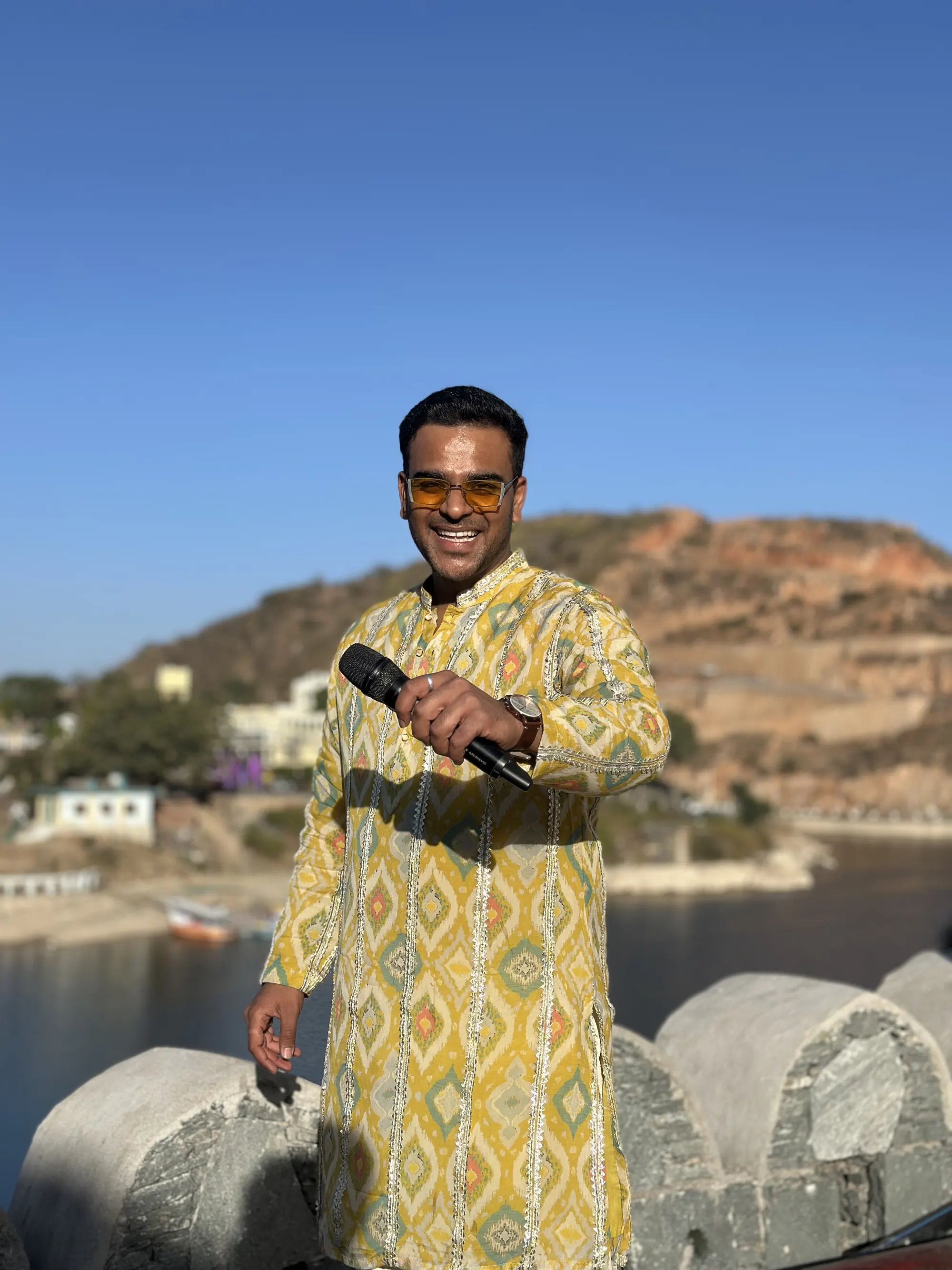 Chirag Vithalani in a yellow kurta with a microphone under a blue sky