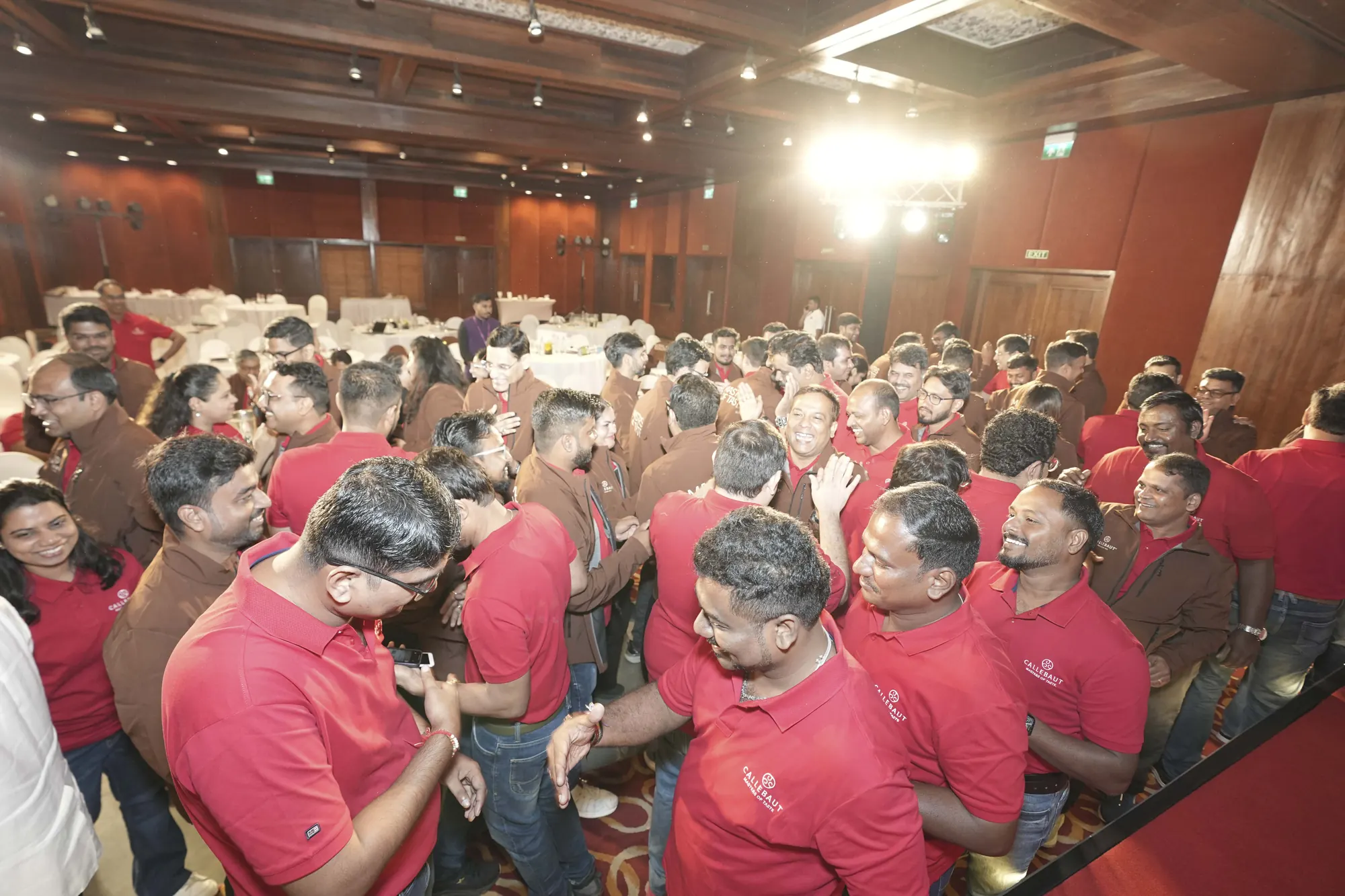 A packed conference hall of delegates in team jackets during a high-energy session