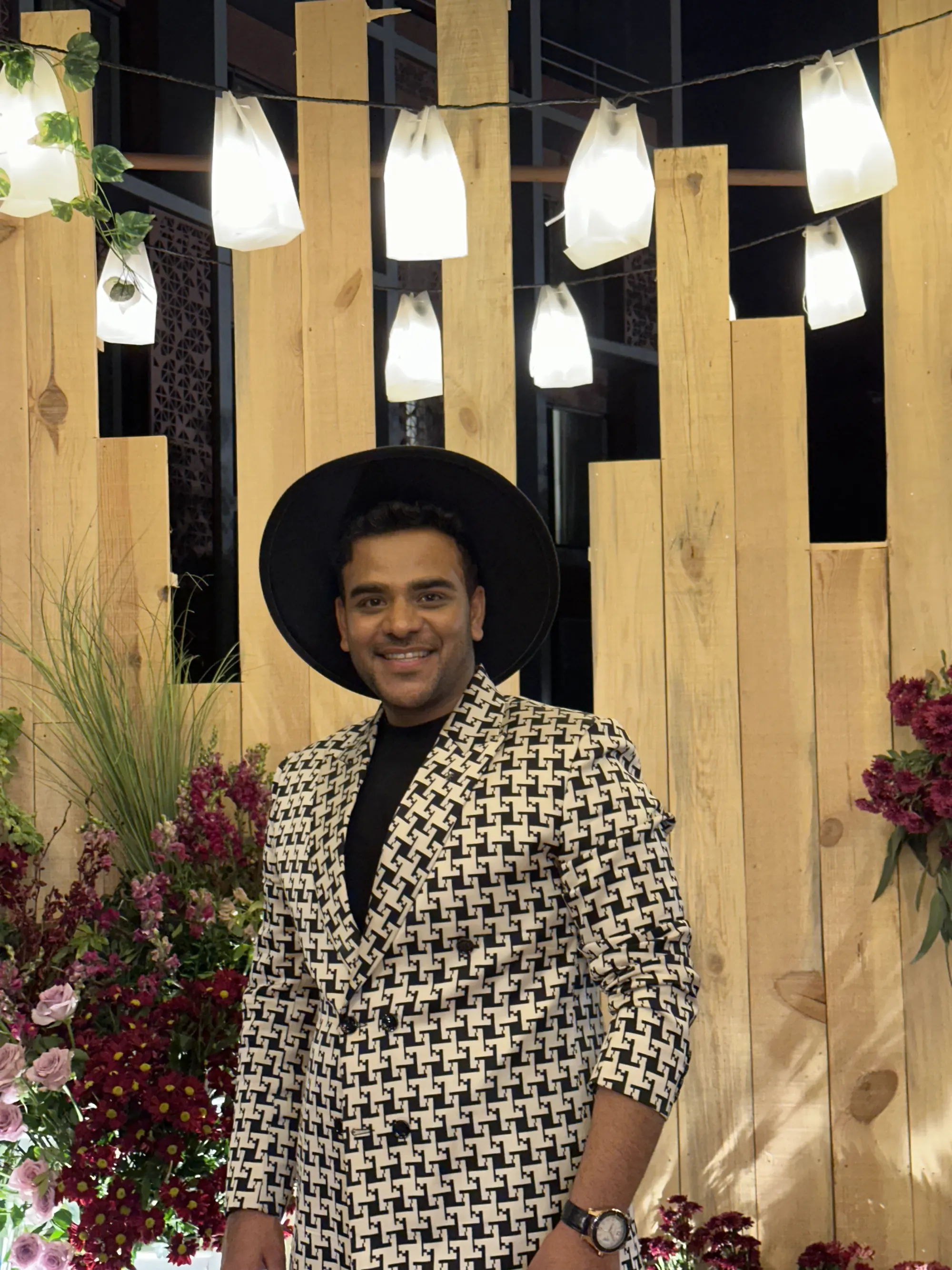 Chirag Vithalani in a houndstooth suit and black hat under hanging lanterns