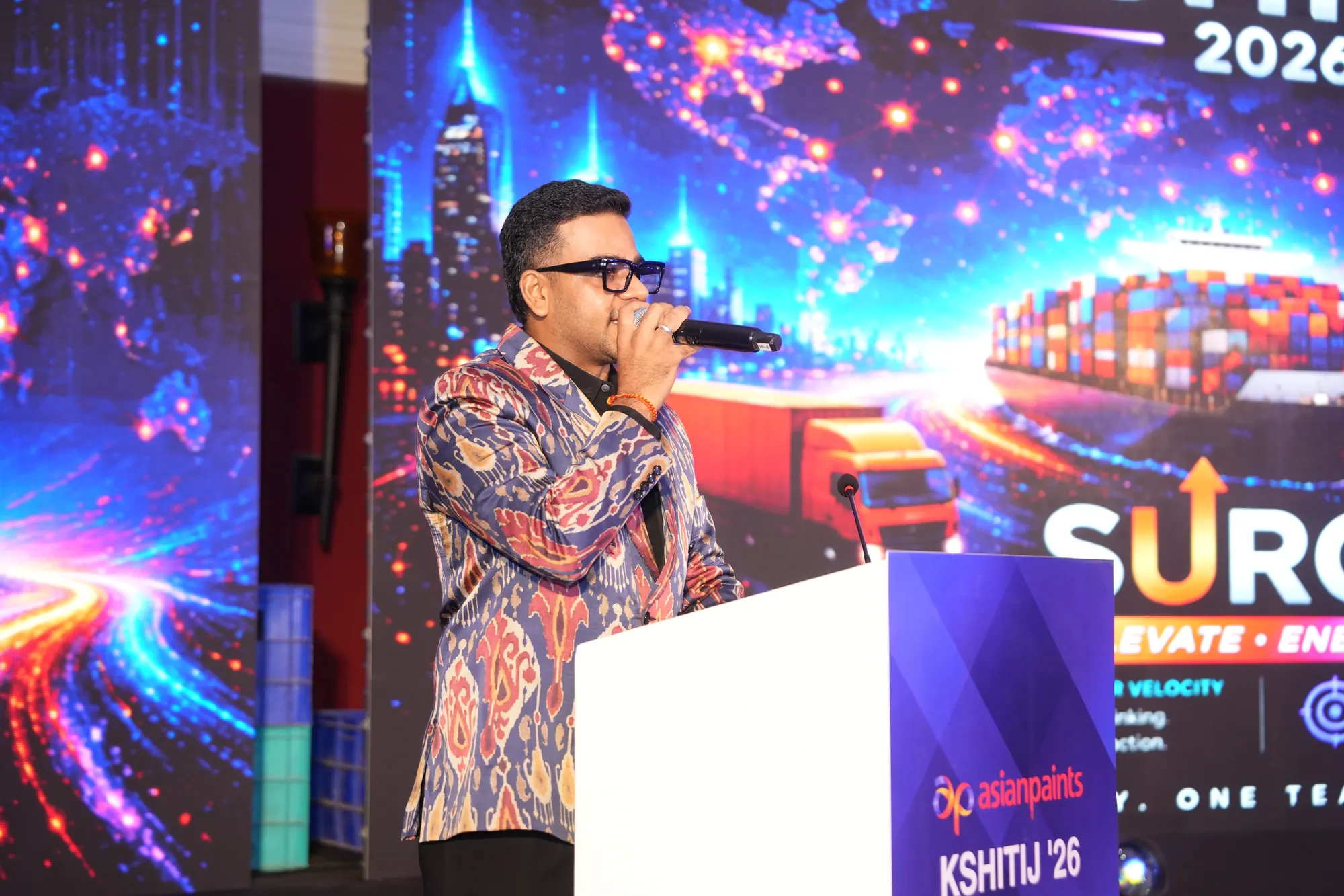 Chirag Vithalani hosting Asian Paints' Kshitij 2026 Surge meet in front of a vivid LED wall