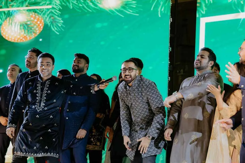 Chirag Vithalani dancing with guests against a green stage at Raj and Sanchi's wedding