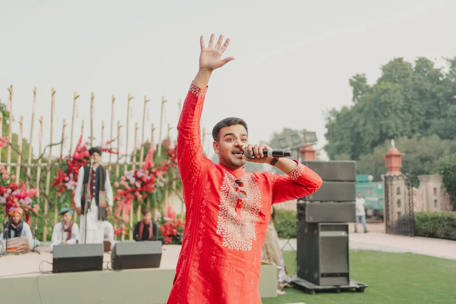 Chirag Vithalani in a red kurta with arm raised on the lawns of Rambagh Palace