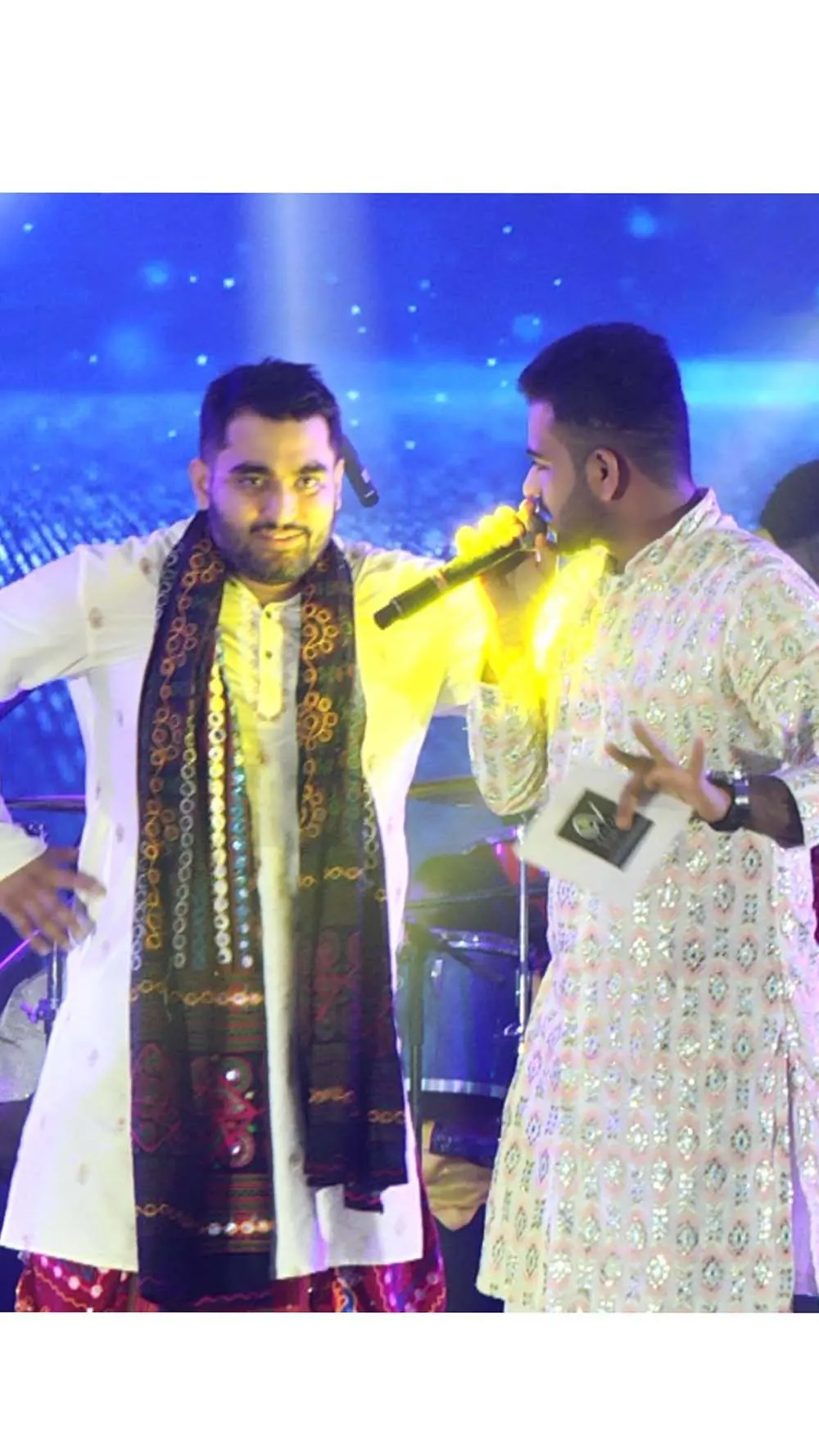 Chirag Vithalani on stage beside a singer under blue concert lights
