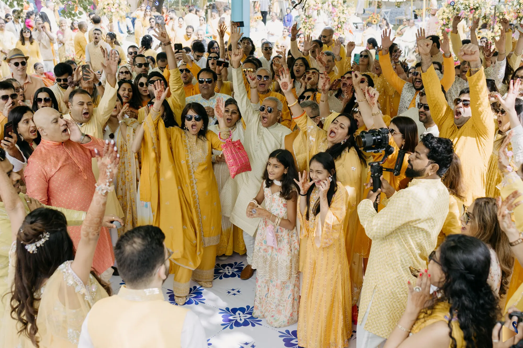 A crowd in yellow cheering at Bartolo and Shivani's haldi, Udaivillas